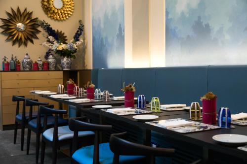 a row of tables in a restaurant with blue walls and chairs at Hotel Indigo Milan - Corso Monforte, an IHG Hotel in Milan