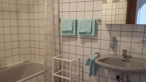 a white tiled bathroom with a sink and a tub at Appartementhaus Lang in Mörbisch am See