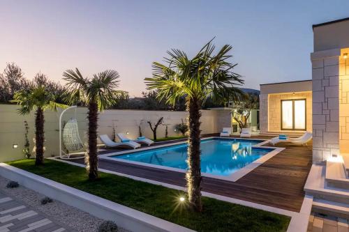 una piscina con palmeras en un patio trasero en Maglica Exclusive Residence, en Kaštela