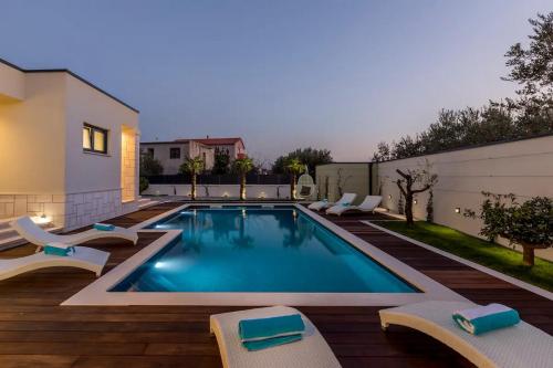 una piscina con sillas y una casa en Maglica Exclusive Residence, en Kaštela