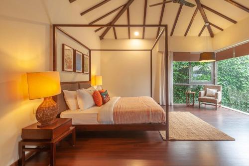 a bedroom with a bed with a lamp and a chair at Bella Norma with Pool - North Goa at StayVista in Calangute