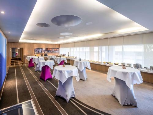 a dining room with white tables and purple chairs at Pullman Brussels Centre Midi in Brussels