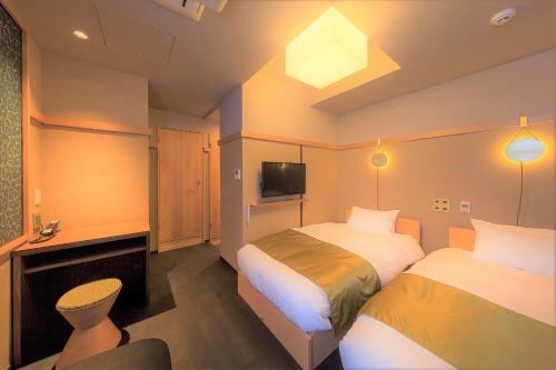 a hotel room with two beds and a tv at Gozan Hotel & Serviced Apartment Higashiyama Sanjo in Kyoto