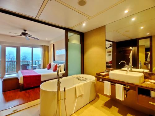a bathroom with a tub and a bedroom with a bed at Fariyas Resort Lonavala in Lonavala