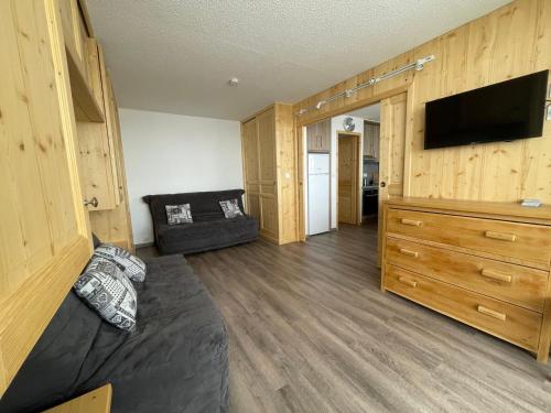 Cette chambre comprend un lit, une commode et une télévision. dans l'établissement Appartement rénové au pied des pistes avec balcon exposé sud pour 4 personnes - FR-1-452-365, aux Menuires