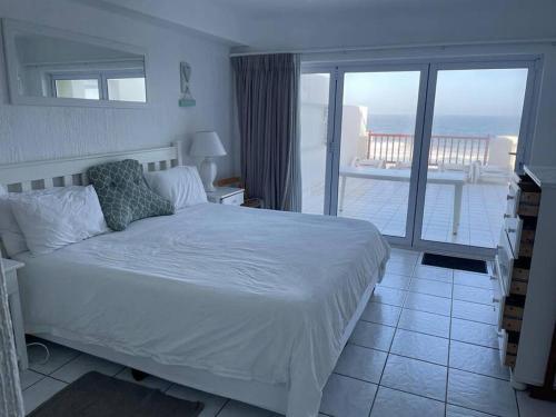 a bedroom with a white bed and a balcony at 9 Skiathos - Beach front apartment - Salt Rock in Ballito