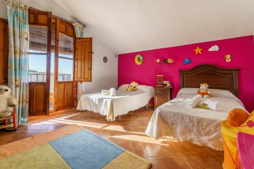 1 Schlafzimmer mit 2 Betten und einer rosa Wand in der Unterkunft CT 186 - El Señorio de Alameda in Alameda