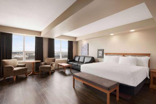 une chambre d'hôtel avec un lit et un canapé dans l'établissement Royal Hotel Edmonton Airport Trademark Collection By Wyndham, à Leduc
