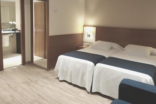 a hotel room with two beds and a mirror at Hotel RH Sorolla Centro in Valencia