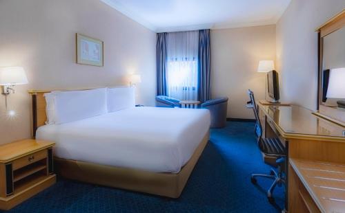 a hotel room with a large white bed and a desk at Holiday Inn Yanbu by IHG in Yanbu