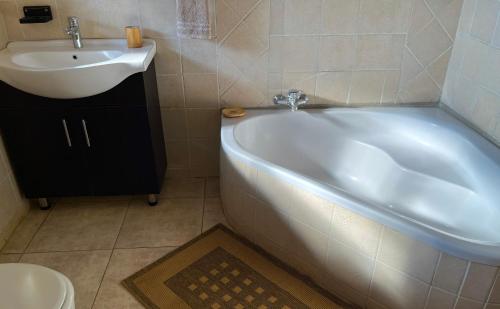 een badkamer met een wit bad en een wastafel bij Bundox Villas in Hoedspruit