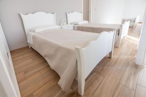 a white bedroom with a white bed and wooden floors at VICOLO MURO in Molfetta