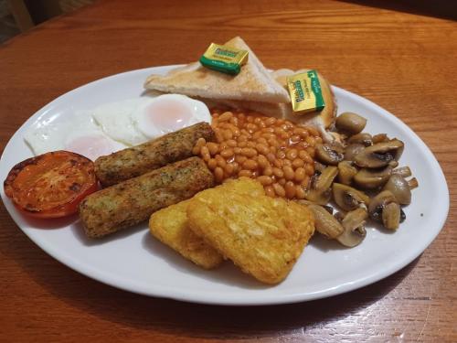 a plate of food with eggs sausage beans and mushrooms at Harry's Hotel & Restaurant in Aberystwyth