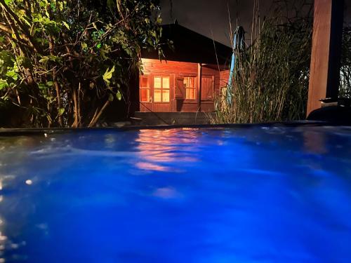 een blauw zwembad voor een huis 's nachts bij Buddha style family house & jacuzzi & sauna near Amsterdam in Vijfhuizen