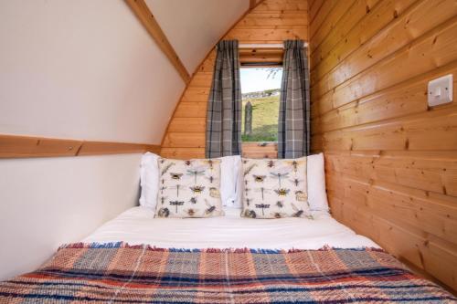 een bed in een kleine kamer met een raam bij Humble Bee Farm Glamping in Folkton