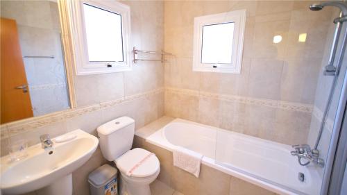 a bathroom with a sink and a tub and a toilet at Kapparis Holiday Villa 114 in Protaras
