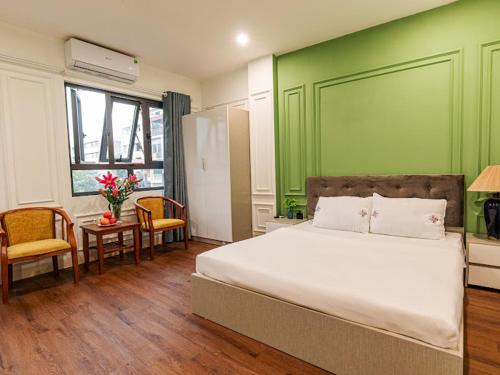 1 dormitorio con cama y pared verde en Madelise Max Hotel, en Hanói