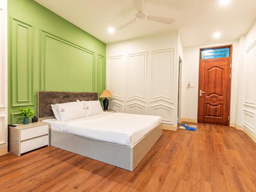 a bedroom with a white bed and green walls at Madelise Max Hotel in Hanoi