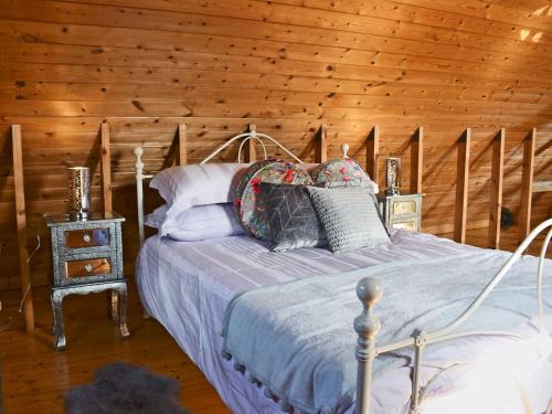 1 dormitorio con 1 cama y pared de madera en The Coach House en Peldon