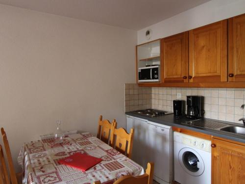 une cuisine avec une table et une machine à laver dans l'établissement Appartement cosy, 5 pers, centre village, proche pistes, balcon, parking, WIFI, draps inclus - FR-1-508-52, à Lanslevillard