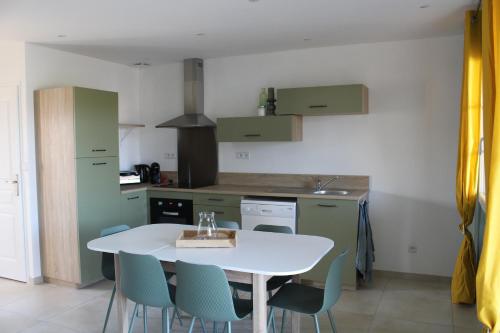 une cuisine avec une table blanche et des chaises bleues dans l'établissement Gîte Rose, Séjour détente et bien être en famille avec jacuzzi, à Fontenay-le-Comte