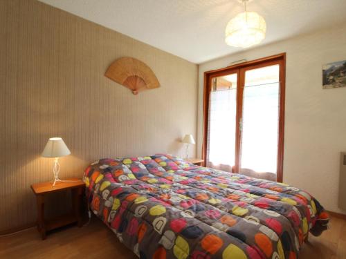 um quarto com uma cama com um edredão colorido e uma janela em Appartement Lanslevillard, 3 pièces, 6 personnes - FR-1-508-58 em Lanslevillard