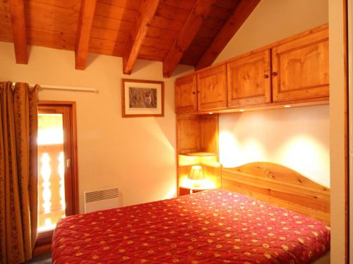 a bedroom with a bed with a red comforter at Appartement Aussois, 3 pièces, 6 personnes - FR-1-508-88 in Aussois