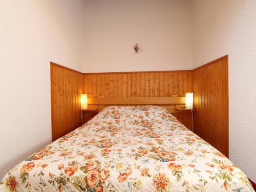 a bed with a floral comforter in a bedroom at Appartement Lanslevillard, 2 pièces, 6 personnes - FR-1-508-112 in Lanslevillard