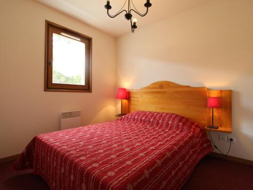 a bedroom with a bed with a red comforter and a window at Appartement Lanslevillard, 3 pièces, 6 personnes - FR-1-508-46 in Lanslevillard