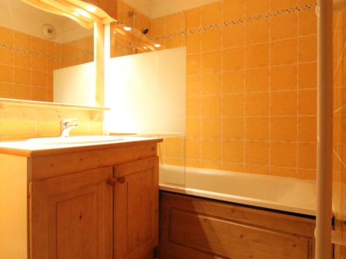 La salle de bains est pourvue de carrelage orange, d'un lavabo et d'une baignoire. dans l'établissement Appartement Confort 4 Pers, Pied des Pistes, Parking Inclus, Lanslevillard-Val Cenis - FR-1-508-119, à Lanslevillard