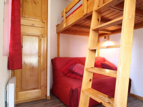 Cama elevada en habitación con sofá rojo en Appartement Lanslevillard, 2 pièces, 4 personnes - FR-1-508-123, en Lanslevillard