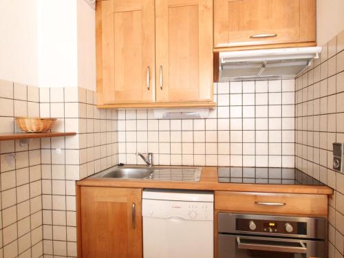 Elle comprend une petite cuisine avec des placards en bois et un évier. dans l'établissement Appartement 7 pers à Val Cenis Lanslebourg, proche pistes avec balcon et garage - FR-1-508-98, à Lanslebourg-Mont-Cenis