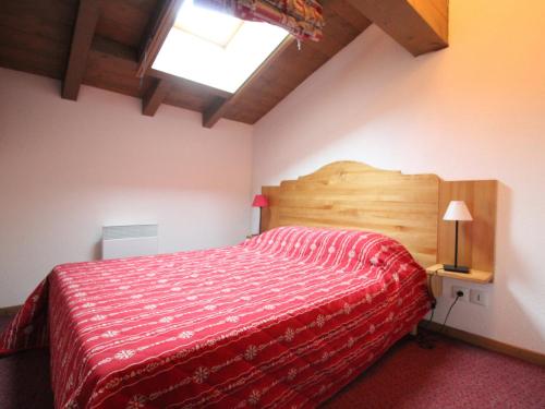 a bedroom with a wooden bed with a red bedspread at Appartement 4 pers à Val Cenis, au pied des pistes, parking, WIFI et balcon - FR-1-508-145 in Lanslevillard