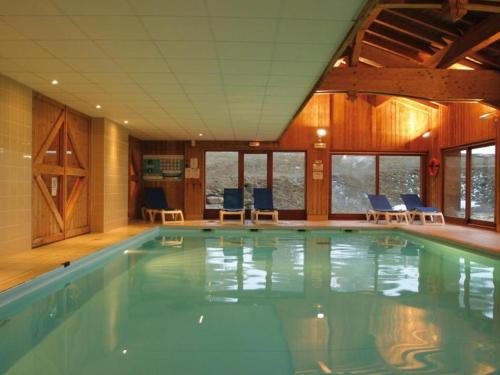 une grande piscine avec des chaises bleues dans un immeuble dans l'établissement Appartement cosy 6 pers avec piscine, sauna, hammam - Val-Cenis, proche pistes et ESF - FR-1-508-97, à Lanslebourg-Mont-Cenis