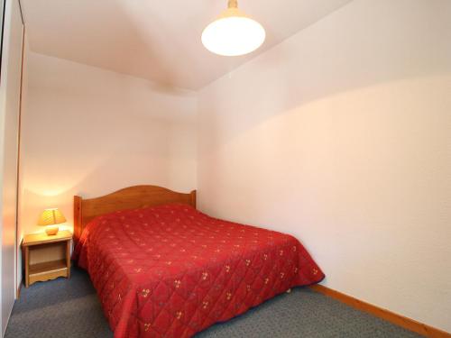 a small bedroom with a red bed and a lamp at Appartement Lanslevillard, 2 pièces, 6 personnes - FR-1-508-107 in Lanslevillard
