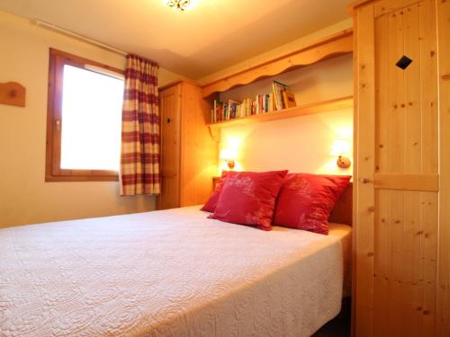 a bedroom with a bed with red pillows and a window at Appartement Lanslebourg-Mont-Cenis, 3 pièces, 6 personnes - FR-1-508-105 in Lanslebourg-Mont-Cenis