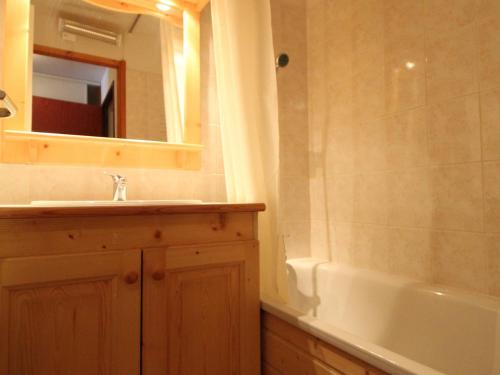 een badkamer met een wastafel, een spiegel en een bad bij Appartement Lanslevillard, 2 pièces, 6 personnes - FR-1-508-107 in Lanslevillard