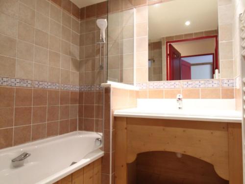 a bathroom with a tub and a sink and a mirror at Appartement Lanslebourg-Mont-Cenis, 2 pièces, 4 personnes - FR-1-508-181 in Lanslebourg-Mont-Cenis