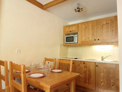 - une cuisine avec une table en bois, des chaises et un four micro-ondes dans l'établissement Appartement cosy 4 pers. pied des pistes avec parking et piscine - Lanslebourg - FR-1-508-181, à Lanslebourg-Mont-Cenis