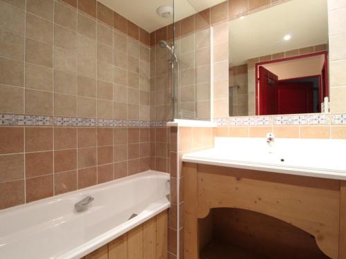 a bathroom with a tub and a sink and a mirror at Appartement Lanslebourg-Mont-Cenis, 2 pièces, 4 personnes - FR-1-508-143 in Lanslebourg-Mont-Cenis