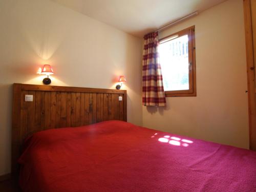 a bedroom with a red bed and a window at Appartement Lanslebourg-Mont-Cenis, 2 pièces, 4 personnes - FR-1-508-149 in Lanslebourg-Mont-Cenis