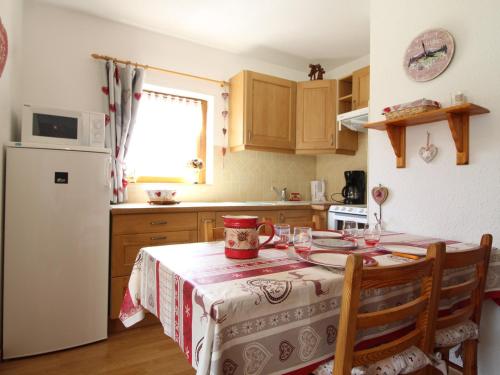 une cuisine avec une table et un réfrigérateur blanc dans l'établissement Appartement cosy pour 4 pers à Val Cenis Haut, proche pistes, balcon sud-ouest, casier à skis - FR-1-508-155, à Lanslevillard