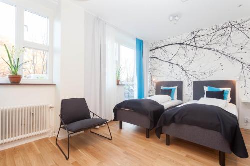 a bedroom with two beds and a chair at ApartDirect Solna in Solna