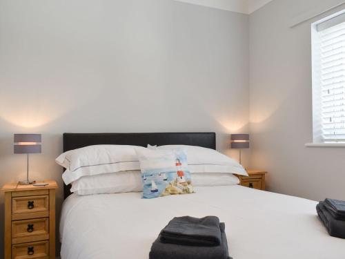 um quarto com uma cama com lençóis brancos e almofadas em Pier View em Gorleston-on-Sea