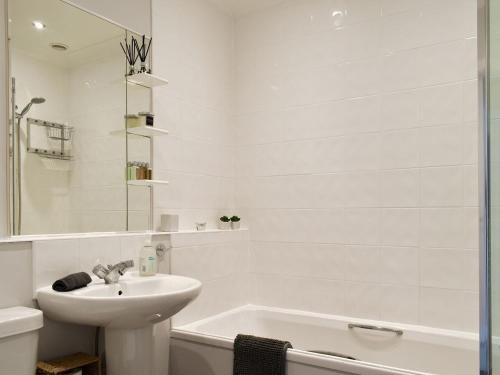 ein weißes Badezimmer mit einem Waschbecken und einer Badewanne in der Unterkunft Pier View in Gorleston-on-Sea