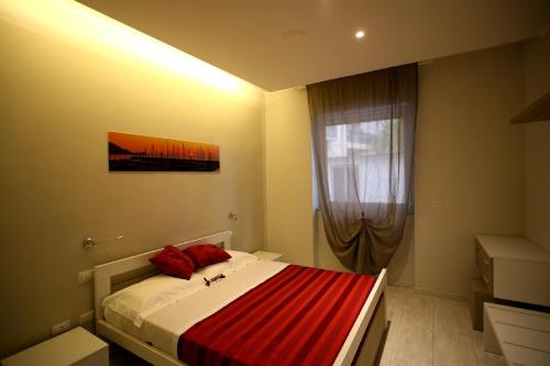 a bedroom with a bed with red pillows and a window at Nina Casa Vacanze in Finale Ligure