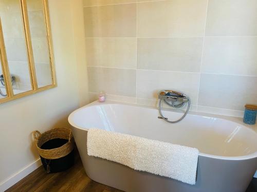 y baño con bañera blanca y espejo. en Chalet Loda cosy spa privé en Roussayrolles