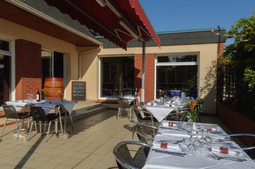 an outdoor patio with tables and chairs with glasses at Hostellerie Saint Vincent Beauvais Aeroport in Beauvais
