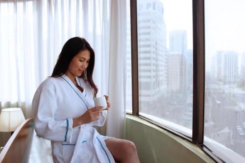 a woman sitting in a chair holding a cup of coffee at Al Diar Dana Hotel in Abu Dhabi