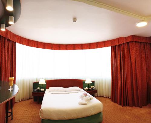 a bedroom with a large bed with red curtains at Al Diar Dana Hotel in Abu Dhabi
